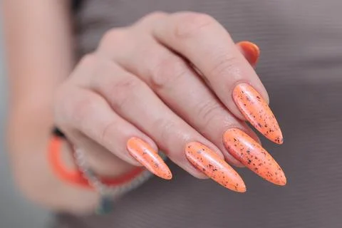 Hand with long nails and light orange neon manicure 스톡 사진