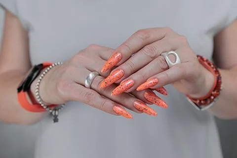 Hand with long nails and light orange neon manicure 스톡 사진