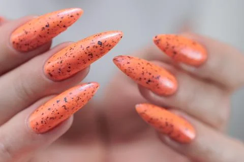 Hand with long nails and light orange neon manicure 写真素材