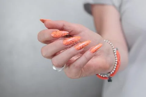 Hand with long nails and light orange neon manicure Stock-Fotos
