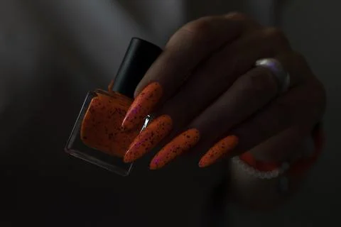 Hand with long nails and light orange neon manicure Stock Photos