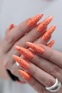 Hand with long nails and light orange neon manicure Stock Photos