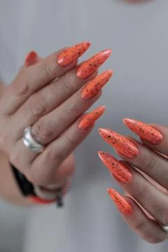 Hand with long nails and light orange coral neon manicure Stock Photos