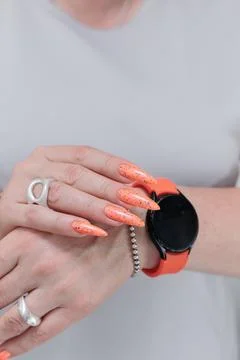 Hand with long nails and light orange neon manicure Stock Photos