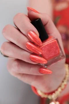 Hand with long nails and light orange neon manicure Photos
