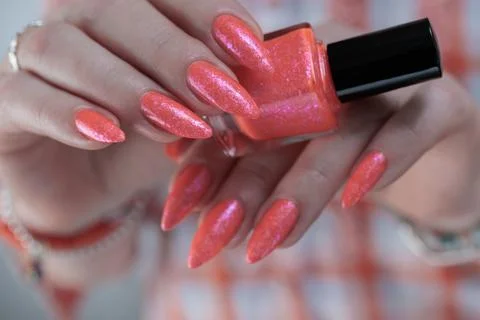 Hand with long nails and light orange coral pink manicure Stock-Fotos