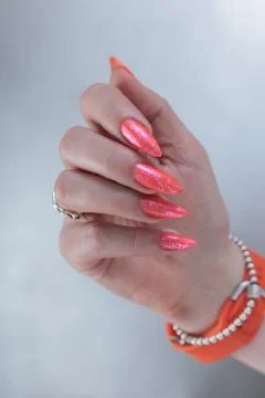 Hand with long nails and light orange coral pink manicure 스톡 사진