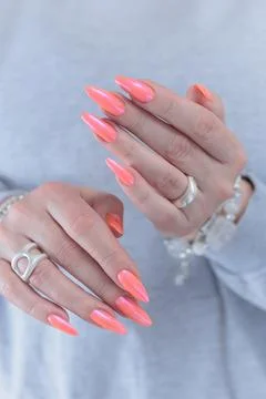 Hand with long nails and light orange coral pink manicure 스톡 사진