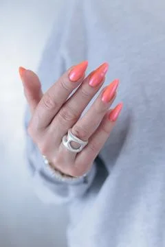 Hand with long nails and light orange coral pink manicure Stock Photos