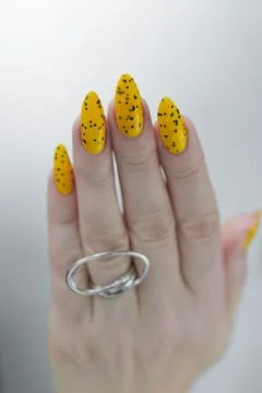 Hand with long nails and a yellow and black nail polish 스톡 사진