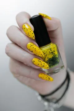 Hand with long nails and a yellow and black nail polish 스톡 사진