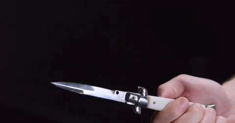 A hand lowers a switch blade into frame and opens it menacingly in slow motion Stock Footage 71782793