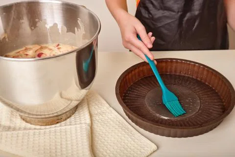 The hand lubricates the baking dish, baking sheet with a brush. The process of Stock Photos