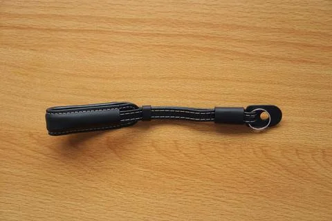 Hand made camera strap in one leather hand isolated on wooden Stock Photos