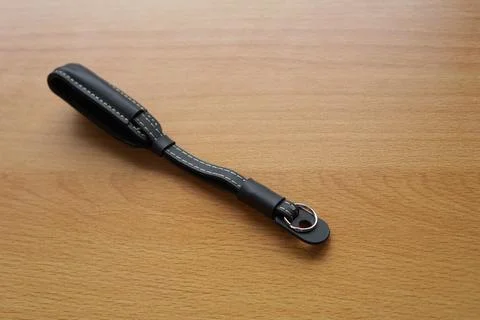 Hand made camera strap in one leather hand isolated on wooden Stock Photos