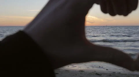 Hand made heart encompassing the sunset at the beach Stock Footage 51463736