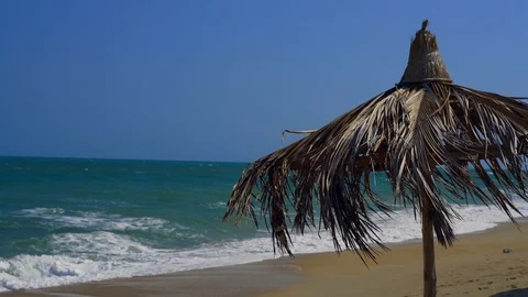 Hand-made straw sunshade on the beach against the ocean background. Stock Footage 127902934