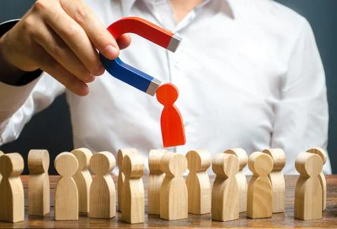 A hand with a magnet pulls red human figure out of the big crowd of people... Stock Photos