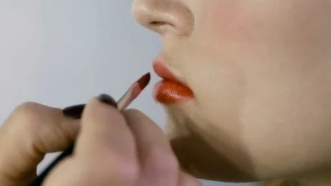 Hand of make-up master, painting lips of young beautiful model. Makeup in 스톡 동영상 82084112
