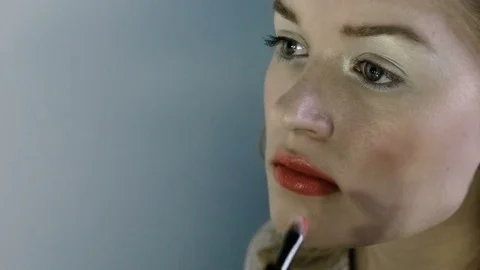 Hand of make-up master, painting lips of young beautiful model. Makeup in 스톡 동영상 82084615