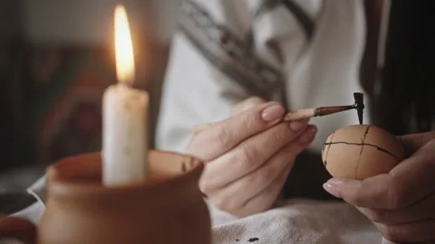 Hand makes patterns on egg heating ethnic tool with candle Stock Footage 219763025