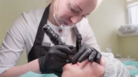 Hand makes permanent makeup lips procedure applying pigment makeup on lips with Video stock 152126652
