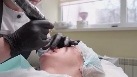 Hand makes permanent makeup lips procedure applying pigment makeup on lips with Video stock 152590099