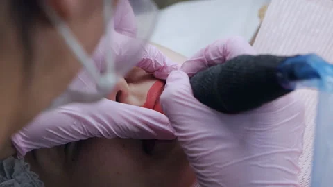 Hand makes permanent makeup lips procedure applying pigment makeup on lips with Stock-Footage 167181342