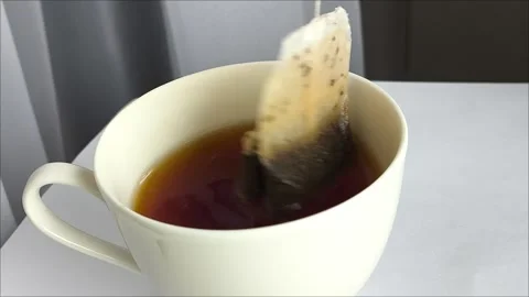 A hand makes tea bags in a white mug and on the kitchen table Vídeos de archivo 311975254