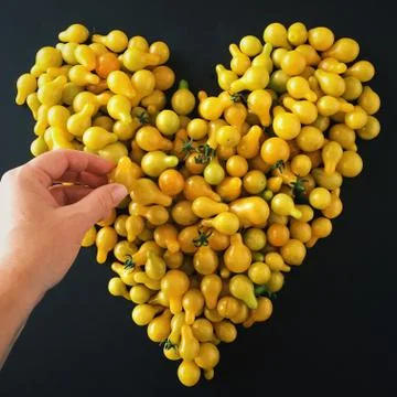 Hand making a heart shape with cherry tomatoes Stock Photos