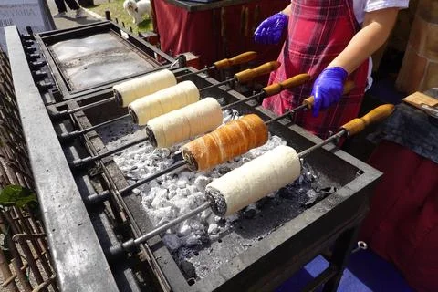 Hand making krt?skalcs chimney cakes over charcoal grill Stock Photos
