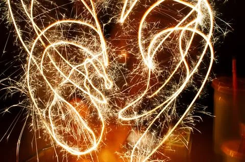 A hand making random circular patterns with a burning fireworks sparkler using  Foto stock