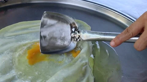 Hand making roti from flour and egg in metal pan and hot oil Stock Footage 141305984