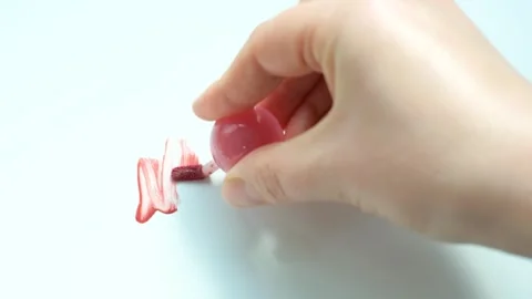 Hand making a smear of pink lipstick on white background top view. Stock Footage 329264460