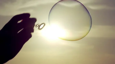 A hand is making soap bubbles in sunset sky background Stock Footage 55418101