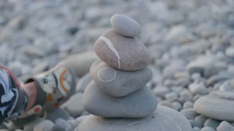 Hand making stone tower on sea beach. Stack of balanced pebbles on beach. Stock Footage 153214702