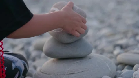 Hand making stone tower on sea beach. Stack of balanced pebbles on beach. Stock Footage 153214969