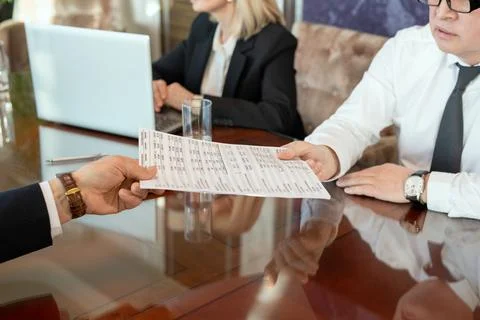 Hand of male delegate passing document with financial data to business partner Stock Photos