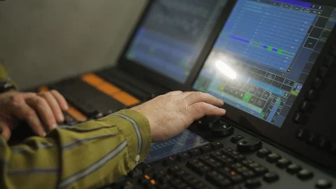 The hand of a male lighting designer at the console programs the stage light for Stock Footage 128392849