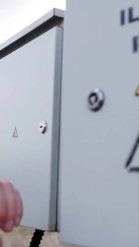 Hand of a male technician unlocking an electrical control box with a key Stock Footage 336948189