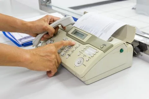 Hand man are using a fax machine in the office Business concept Photos