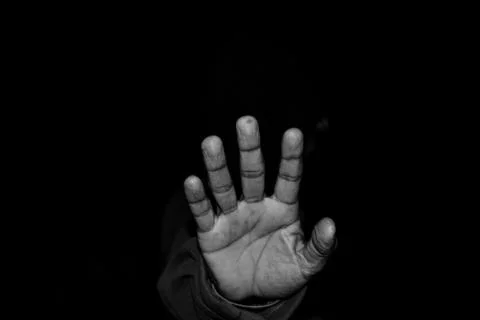 A hand of a man is in the darkness asking for help Stock Photos