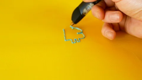 Hand of a man draws with a 3d printer pen the bitcoin symbol on yellow Stock Footage 103376107
