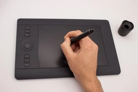 The hand of a man draws a stylus on a graphics tablet. The isolated image on Stock Photos