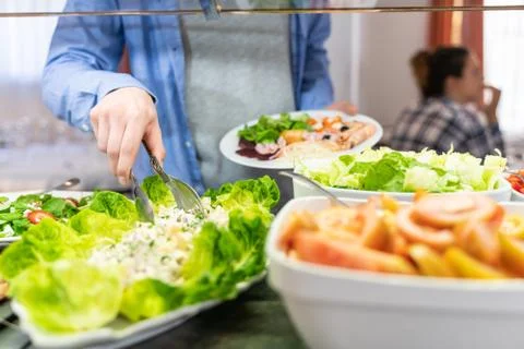 Hand of a man getting salad at a self-service Stock Photos