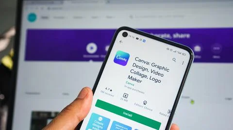 The hand of the man holding an android phone opens the playstore of canva app Stock Photos