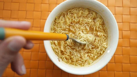 Hand of a man holding a fork with cooked instant noodles from ceramic bowl Stock Footage 127581456