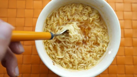 Hand of a man holding a fork with cooked instant noodles from ceramic bowl o Stock Footage 127581830