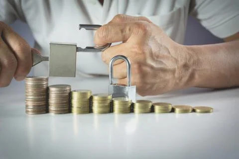 Hand of man holding lock with stack coins for financial, growing and saving b Stock Photos