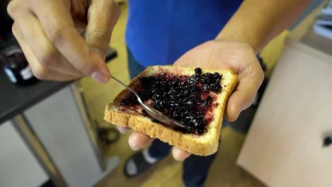 The hand of the man holding the sliced bread and the blueberry jam Video stock 102878681